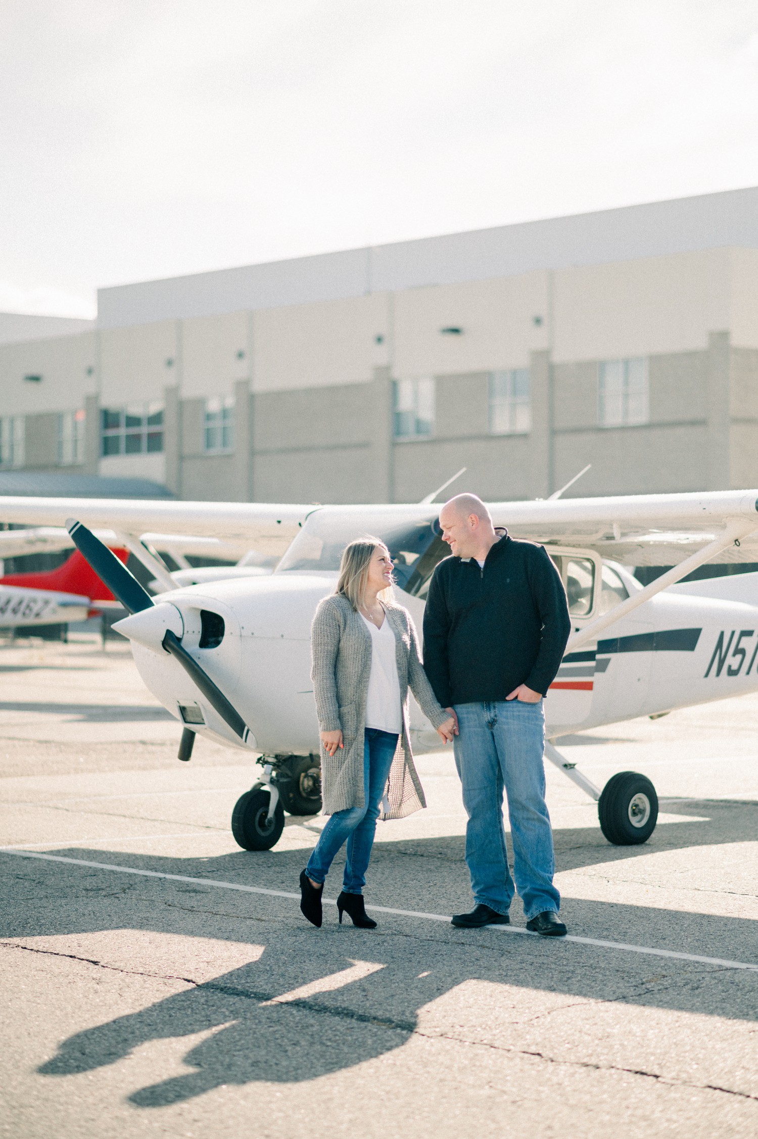 Couple standing by Cessna airplane for engagement photos at Centennial Airport.