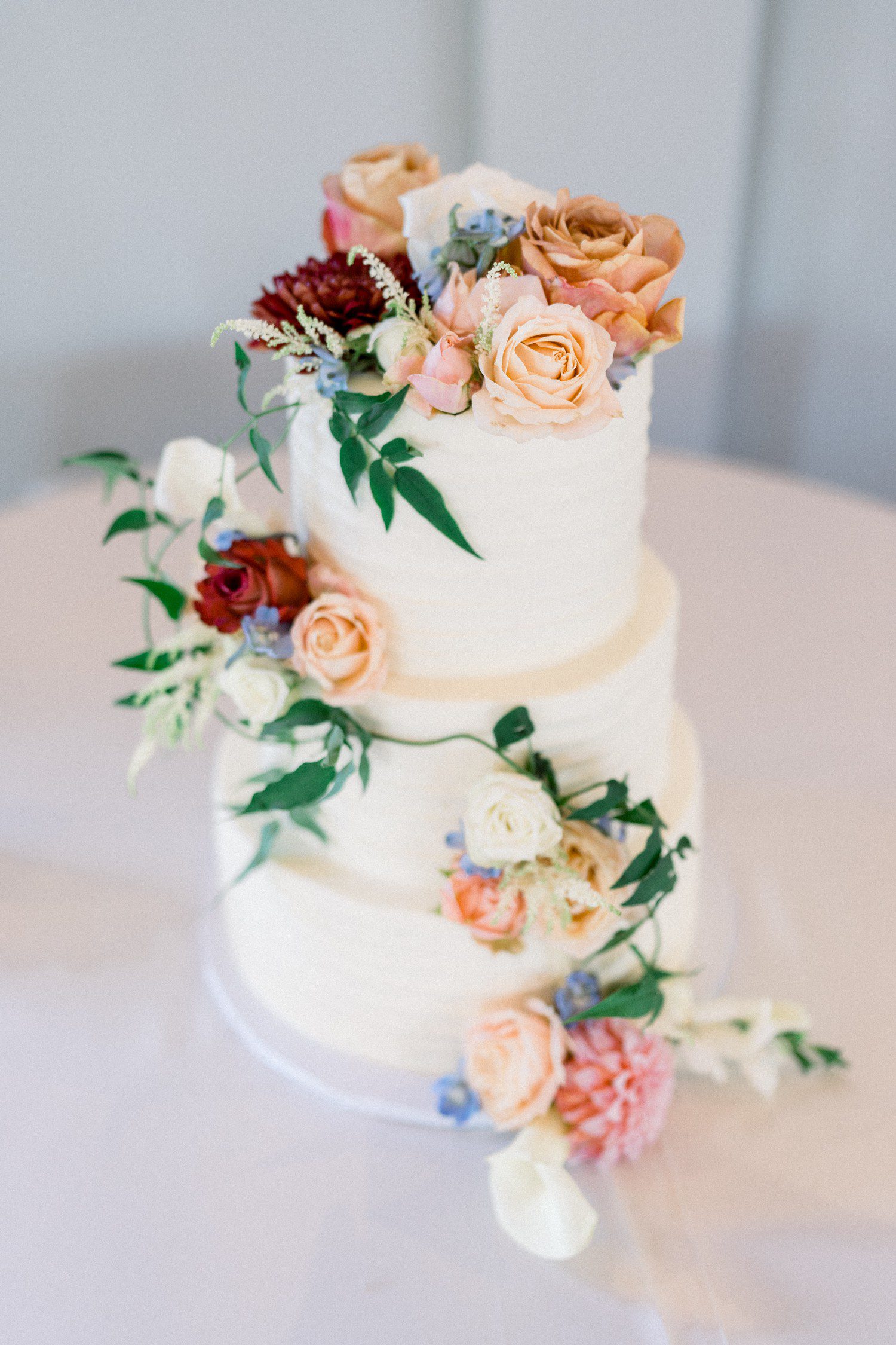 White wedding cake decorated with colorful flowers.