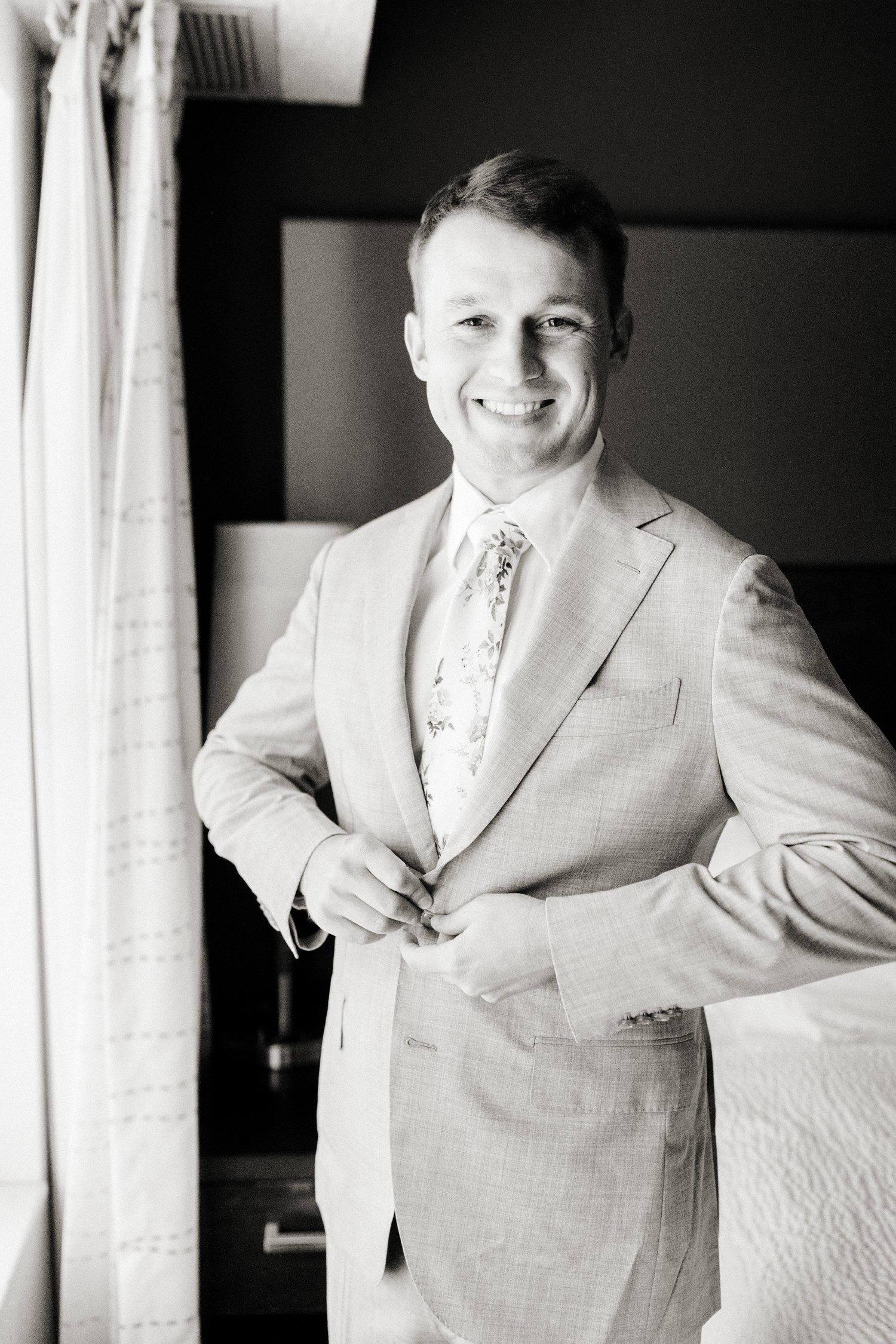 Groom buttoning suit jacket before wedding.