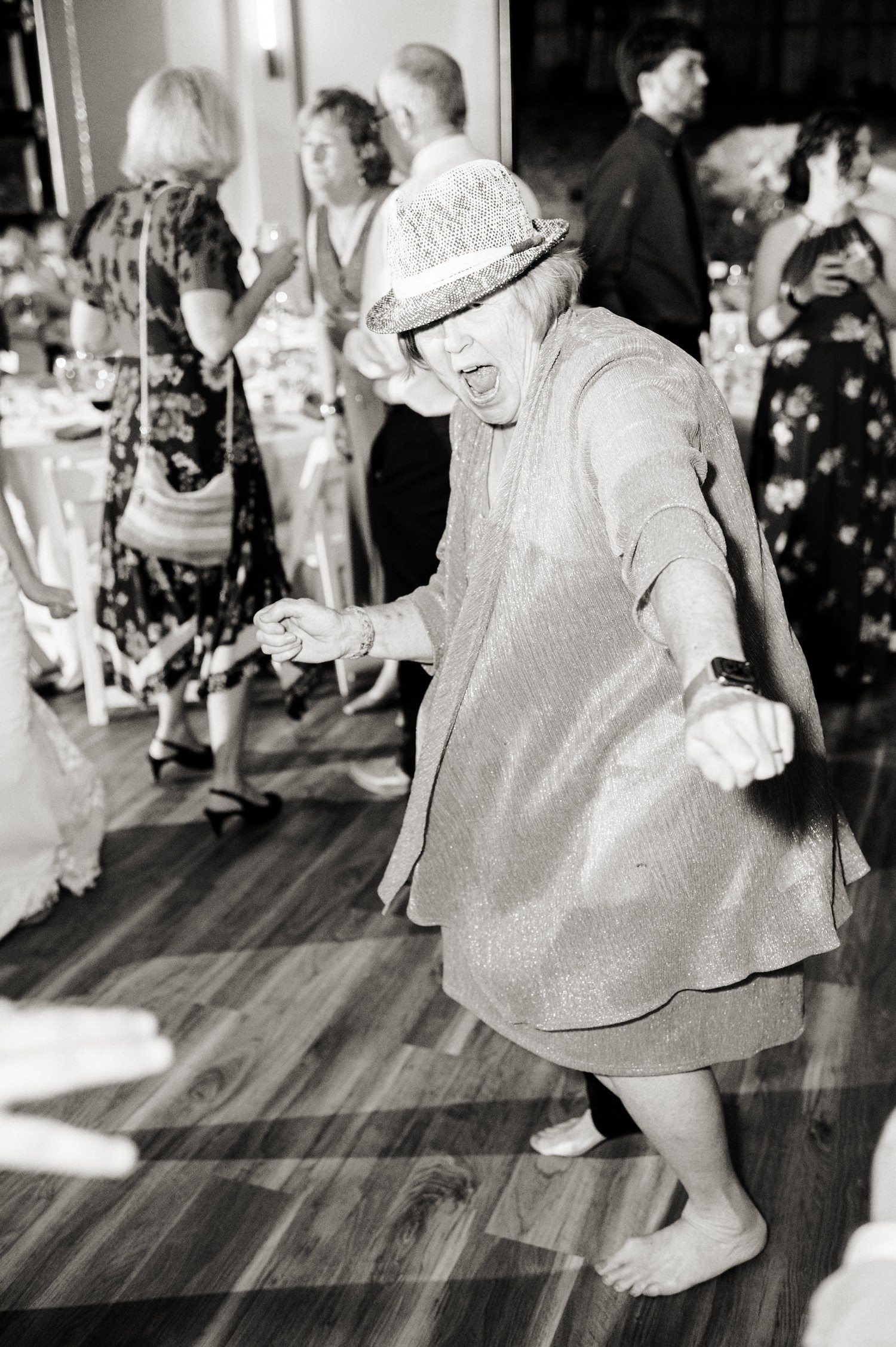 Wedding guest in hat dancing during reception.