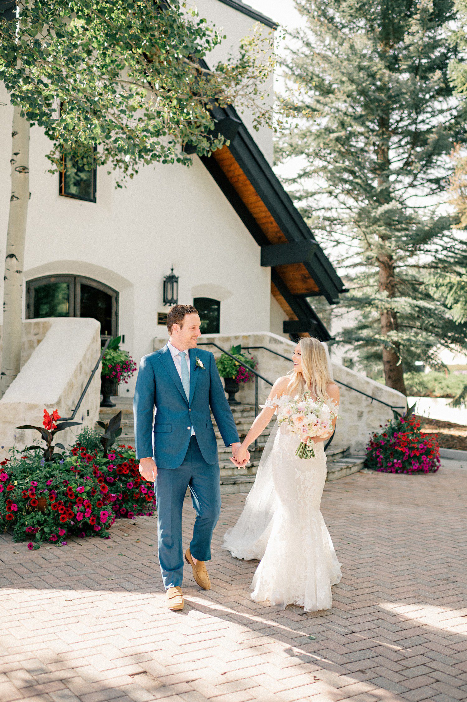 Bride and groom holding hands walking at Vail Chapel after their wedding ceremony. 