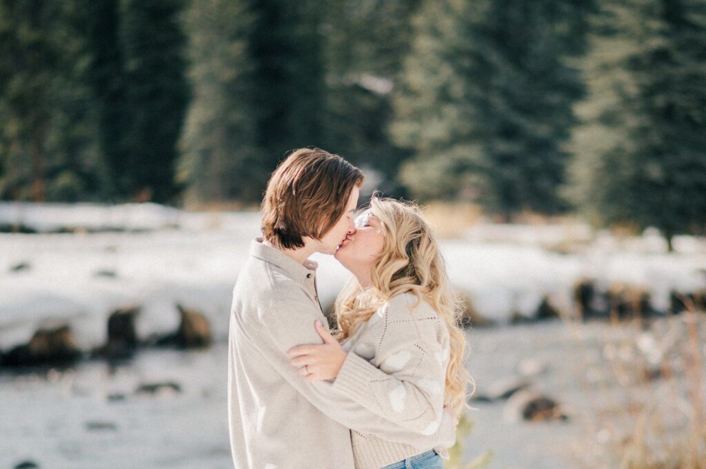 Vail Village engagement photos near Gore Creek with couple kissing. 